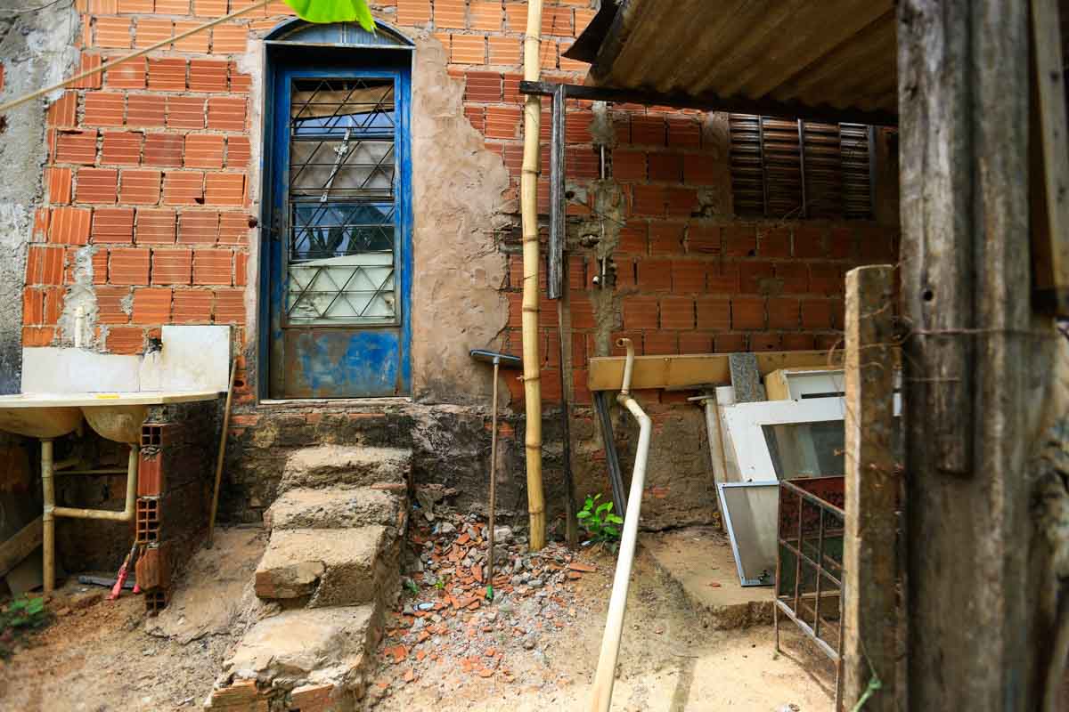 Jane morava em uma casinha vermelha repleta de plantas, perto de uma igreja evangélica